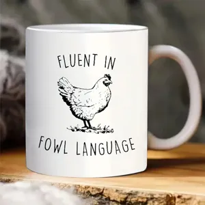 Detalle de cerca de una taza de café de cerámica blanca con gráfico de pollo gracioso.