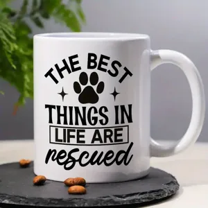 Close-up detail of white ceramic coffee mug featuring black pet rescue quote print design.