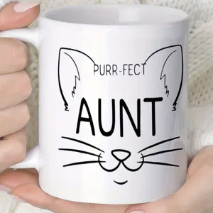 Nahaufnahme einer weißen Keramiktasse mit niedlichem Katzengesicht und Aufdruck.