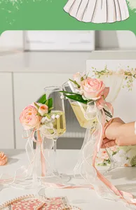 Nahaufnahme von Hochzeits-Champagnergläsern, verziert mit rosa Rosen und edlen Perlenbändern.