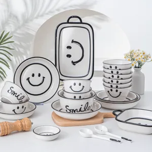 Keramisch servies set met zwart smiley ontwerp, inclusief kommen, borden en lepels.