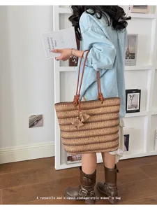 Woven straw tote bag detail showing natural texture, brown straps and chic tassel pendant.