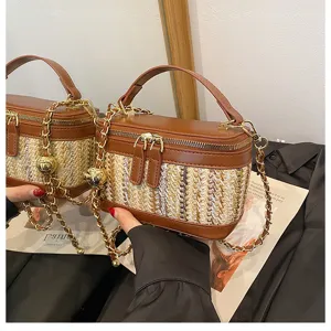 Detailed shot of the woven vanity box bag with brown PU leather trim and gold chain strap.