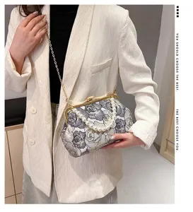 Detailed view of the elegant embroidered pearl handle shoulder bag with gold chain strap.