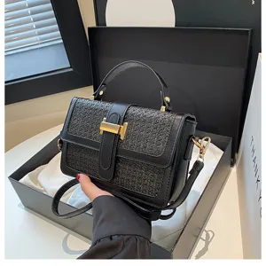 Black woven crossbody bag detail, featuring elegant flap closure and gold-tone T metal hardware.