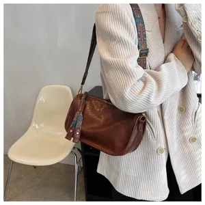 Soft leather brown crossbody shoulder pillow bag with colorful ethnic strap for women daily use.