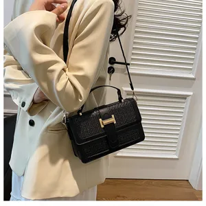 Woven flap crossbody bag detail, featuring metallic H clasp and texture, elegant daily look.