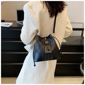 Black woven bucket bag for women, chic straw shoulder handbag with drawstring and buckle detail.