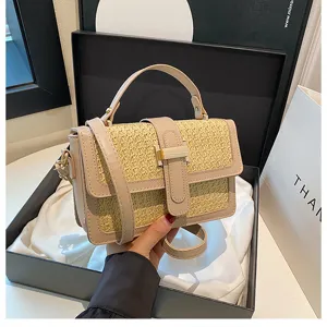 Stylish woven straw crossbody bag with flap cover, top handle, and elegant metal buckle detail.
