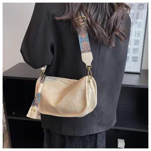 Soft leather pillow crossbody bag detail, ethnic patterned wide strap, stylish casual look.