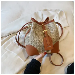 Woven straw bucket bag with brown leather trim, casual shoulder design for summer daily use.