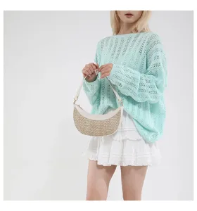Close-up of the stylish straw crescent shoulder bag worn with a light blue knit sweater.