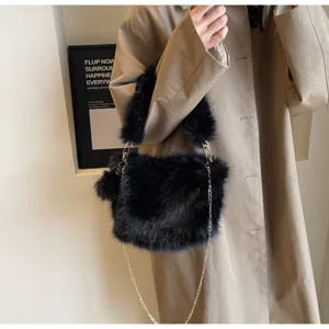 Detailed shot of a stylish black faux fur shoulder bag with a gold chain strap and fluffy charm.