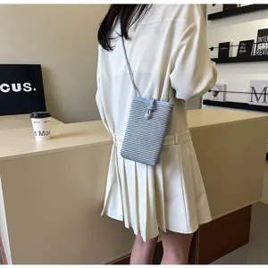Detailed view of a stylish blue and white woven mini crossbody phone bag with pearl accent.