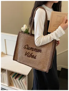 Detailed view of the woven straw shoulder bag with letter embroidery, perfect for beach vacation.