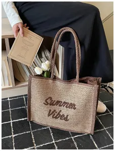 Detailed view of the woven straw tote bag featuring brown braided handles and embroidery.