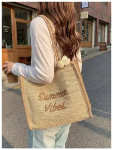 Detail view of the stylish woven straw tote bag with Summer Vibes embroidery, perfect for summer.