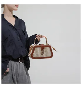 Detail view of woven straw handbag featuring leather trim, metal lock and stylish silk scarf.