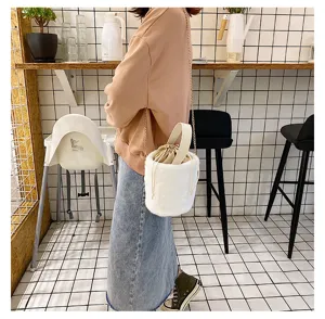 White plush bucket bag detail, fluffy crossbody bag with drawstring closure and chain.