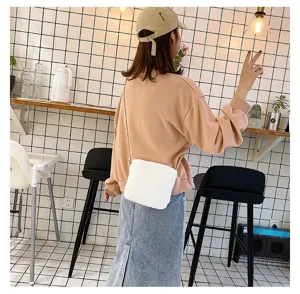 Close-up lifestyle view of the cute white plush crossbody bag in a trendy cafe setting.