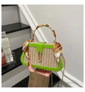 Straw woven crossbody handbag with green leather trim, scarf handle and chain strap.