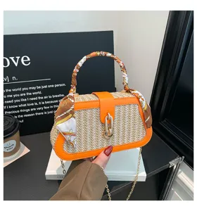 Stylish straw handbag with orange leather trim, scarf wrapped handle and chic chain strap.