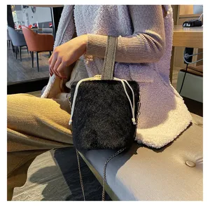 Detailed view of fluffy black bucket bag, soft faux fur texture with chain and drawstring.
