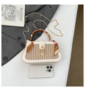 Chic straw woven handbag with elegant silk scarf handle and chain strap for women.