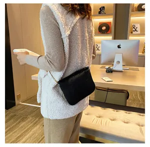 Black plush crossbody bag detail, featuring soft faux fur texture and elegant chain strap style.
