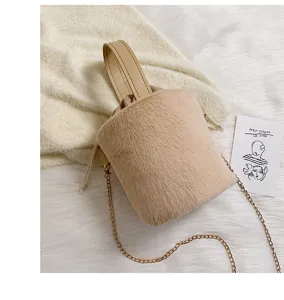 Plush bucket bag detail view, soft faux fur texture with delicate gold chain strap and drawstring.