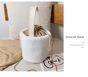 Detail view of stylish white plush bucket bag with leather handle and chain strap.
