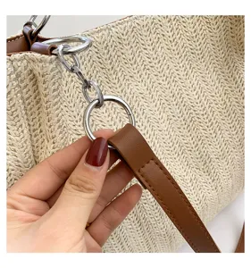 Close-up detail of stylish woven straw bucket shoulder bag with brown leather strap.