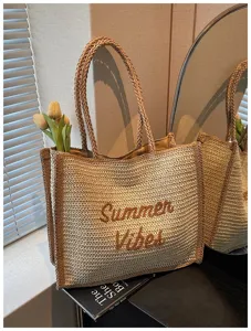 Detailed shot of a woven straw tote bag with Summer Vibes embroidery and dual handles.