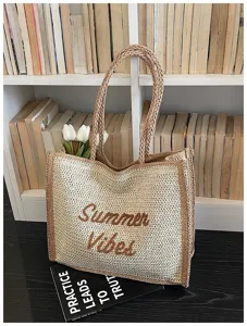 Detailed view of the woven straw tote bag with summer vibe embroidery in natural beige.