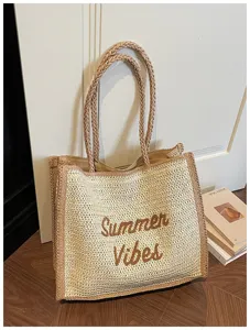 Detailed view of the large woven straw tote bag with embroidered summer lettering, beach style.