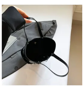 Elegante bolso cubo de charol negro con detalles de tachuelas y asas superiores útiles.