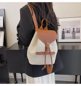 Vue détaillée du sac à dos en paille tissée avec rabat en cuir et cordon de serrage.