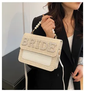Vista dettagliata della borsa da sposa in paglia con perle e tracolla elegante.