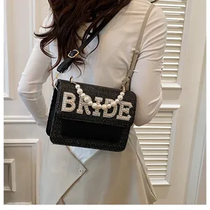 Vista dettagliata di una borsa a tracolla nera intrecciata con perle BRIDE e catena.