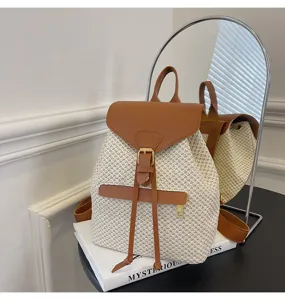 Détail en gros plan du sac à dos en paille tissée avec rabat en cuir PU marron et boucle.