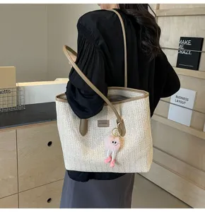 Woven tote bag featuring contrast leather trim, spacious capacity, and a cute plush charm accessory.
