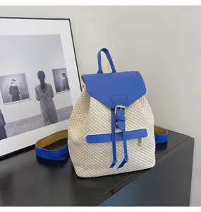 Vue détaillée du sac à dos en paille tissée avec rabat en cuir bleu et boucle, style estival décontracté.