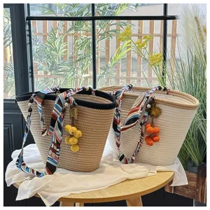 Woven straw bucket tote bag with colorful silk scarf and cute pompom pendant for summer beach.
