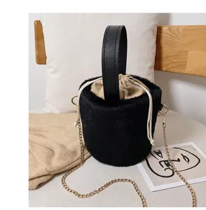 Stylish winter black faux fur bucket bag with top handle and chic gold chain strap for women.