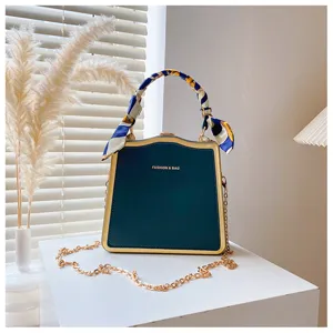 Élégant sac à bandoulière de soirée vert foncé avec bordure dorée, foulard et chaîne.