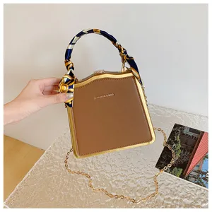 Élégante pochette marron avec cadre en métal doré, poignée en foulard élégant et chaîne.