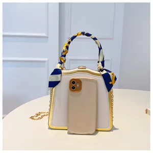 Détail de sac de soirée élégant avec poignée en foulard et chaîne dorée chic.