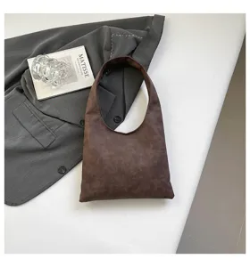 Detailed view of stylish brown minimalist shoulder hobo bag, soft leather texture surface.