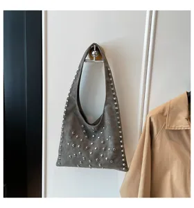 Detail view of grey suede-like shoulder bag decorated with shiny metal rivets for women.