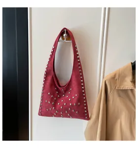 Detail view of a chic red suede shoulder bag featuring stylish metallic studs and comfortable strap.